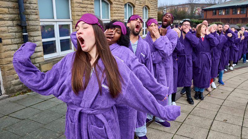 A line of colleagues wearing purple robes yawning in unison.