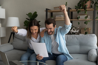 A couple smiling as the man pumps his fist in the air in celebration.