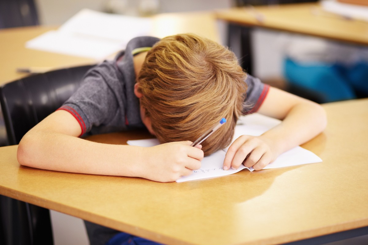 A child asleep at their school desk after a poor night's sleep.