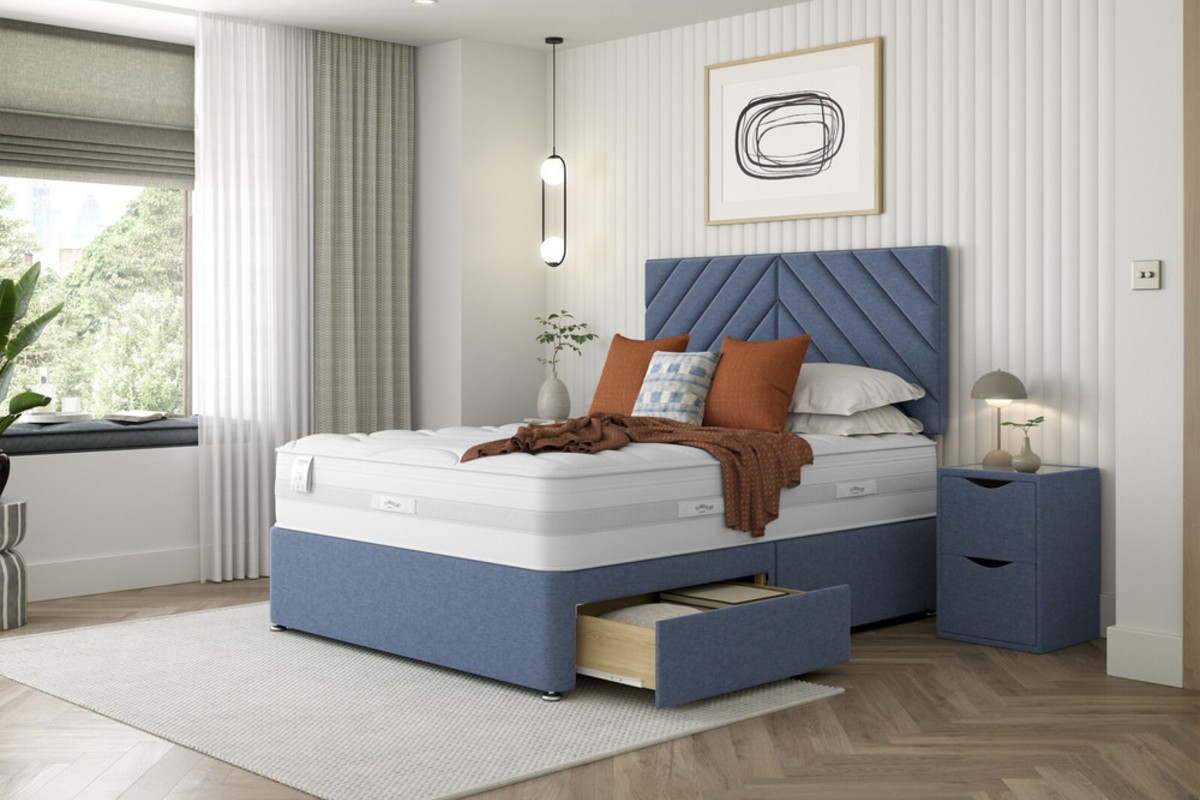 A blue, upholstered divan bed set in a neutral, calming bedroom design.