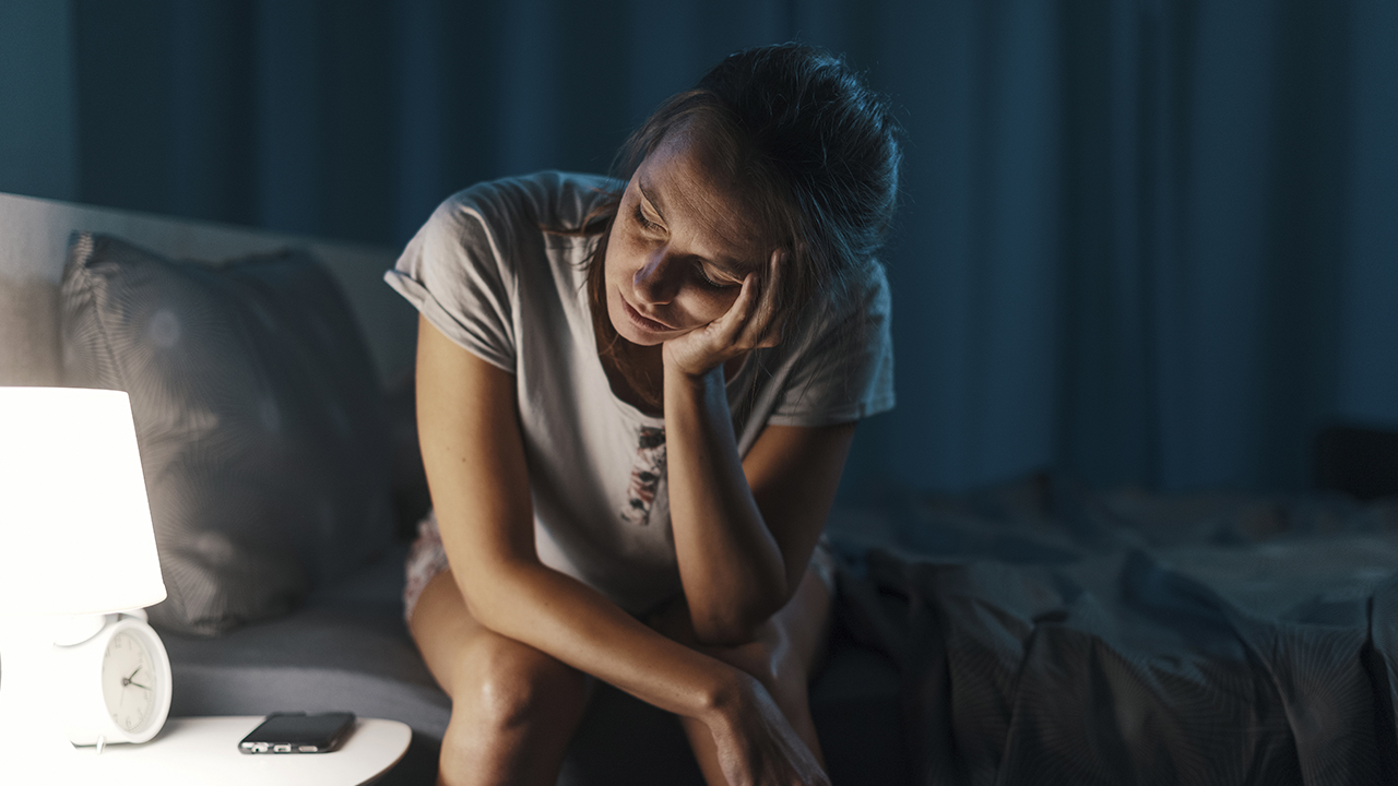 A woman suffering from sleep deprivation as she sits awake in the early hours of the morning.