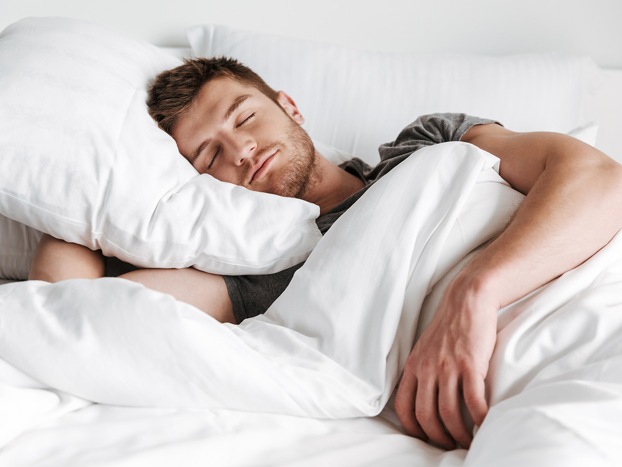 The Great British sleep summary hero image of a man sleeping happily with his head on a pillow and his duvet over him.