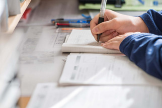 Pupil writing on pad of paper with a pen