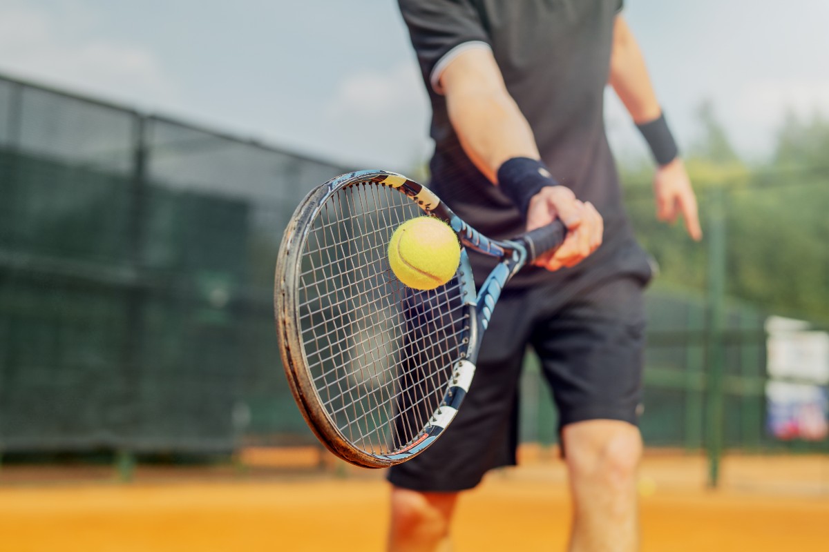 A man swinging a tennis racket at a tennis ball on a court