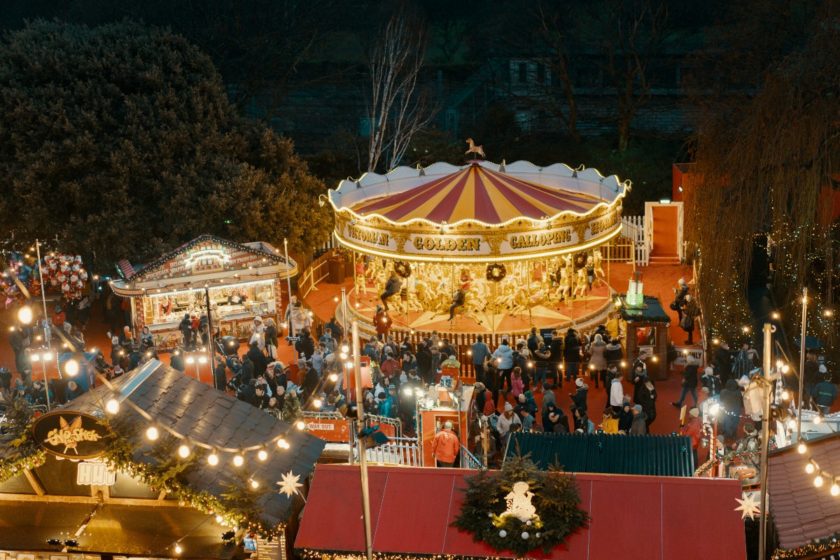 A brightly lit Christmas market with a bustling crowd