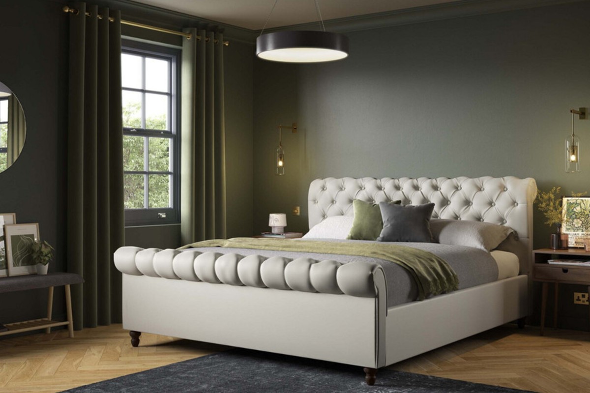 A stylish modern bedroom with a large upholstered bed set against dark green walls.