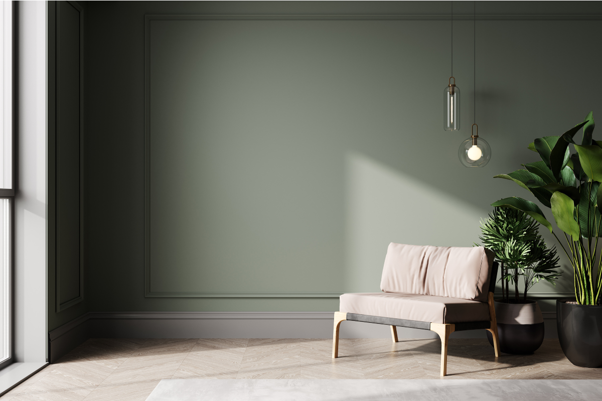 A lone seat and two houseplants set against a pale sage green wall