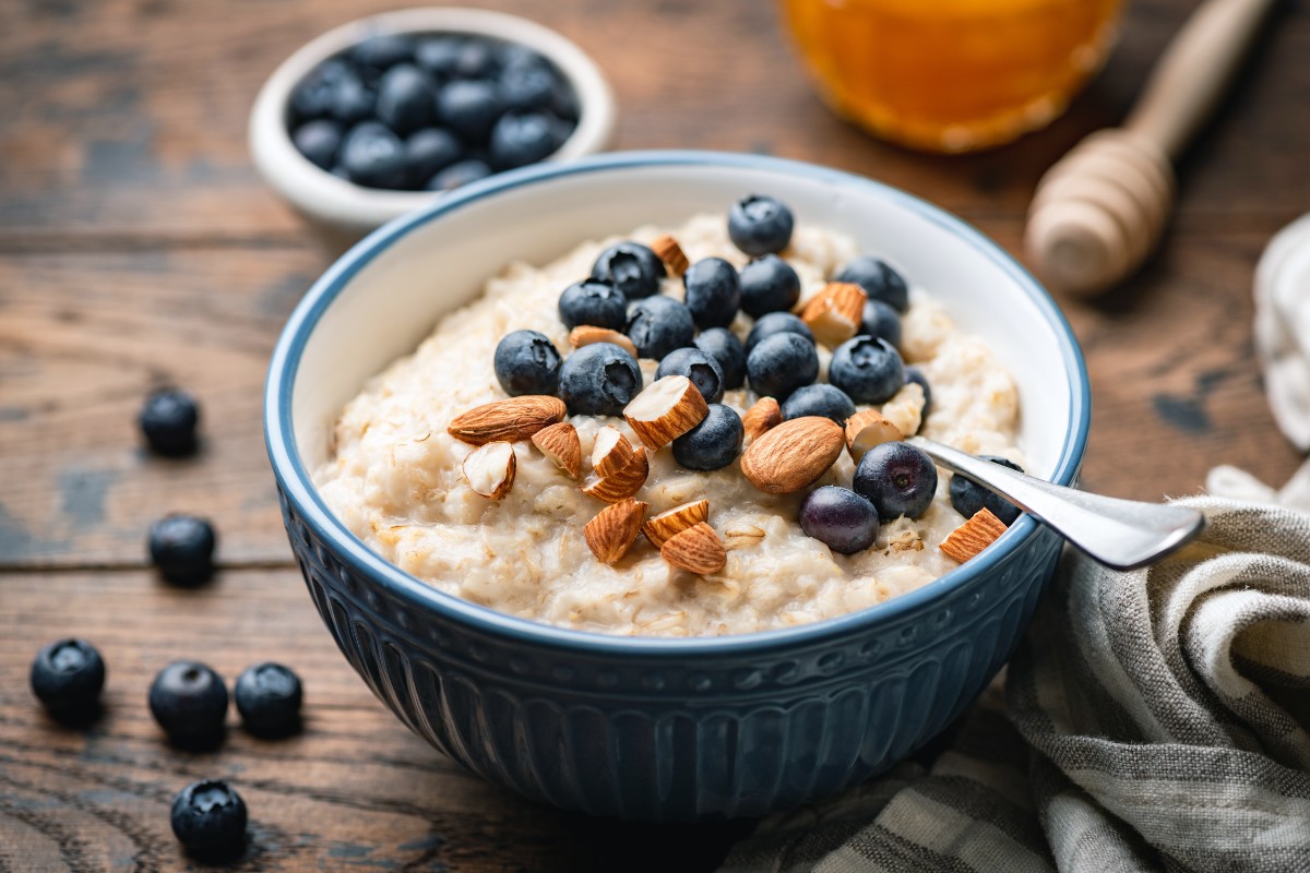 A bowl of porridge with fresh almonds and blueberries scattered on top