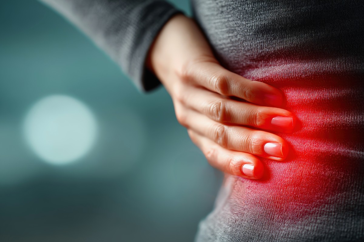 A close up of a woman rubbing her ribs, a red glow highlighting the area she is feeling the intercostal muscle strain.