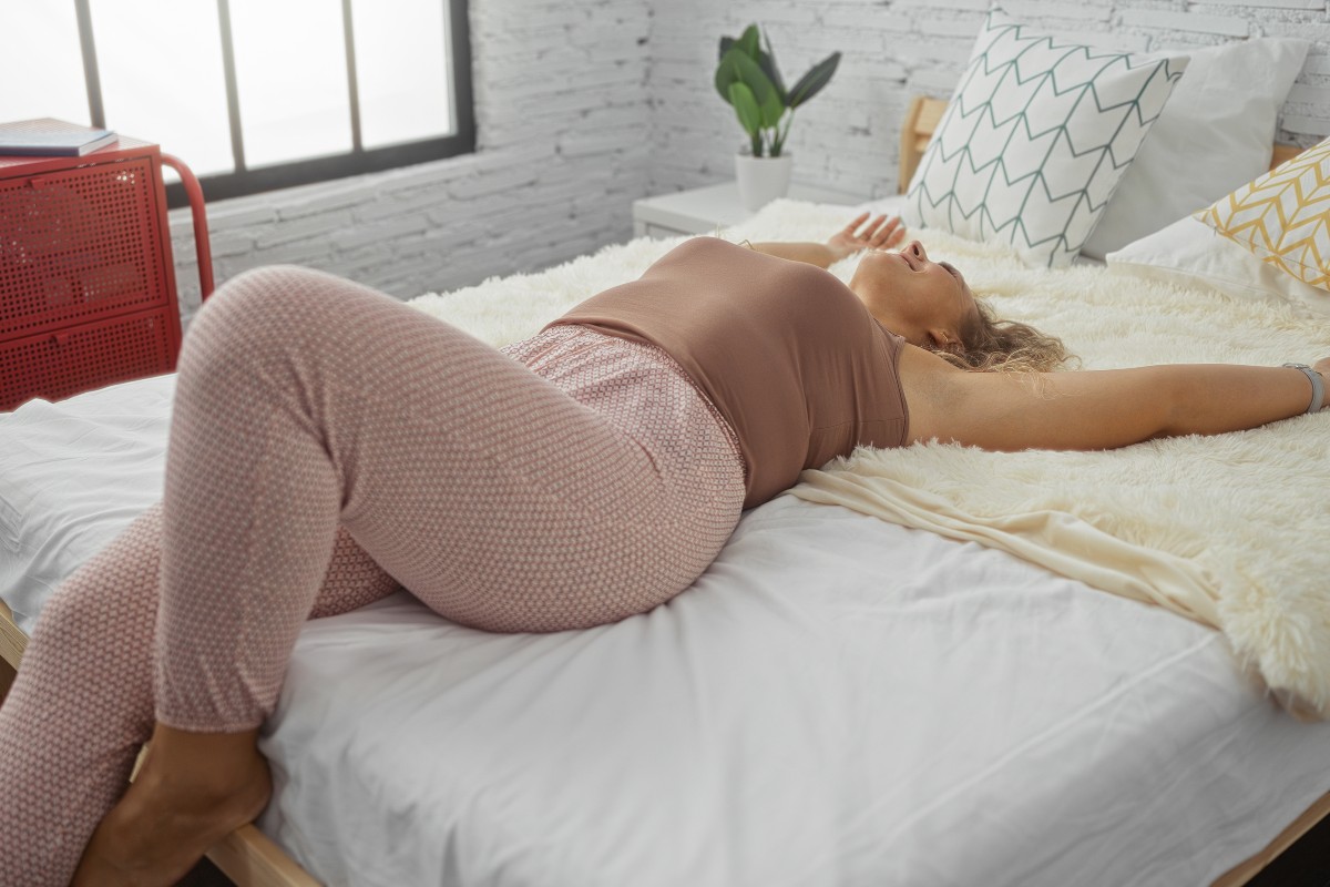 A woman stretching out on a queen size bed