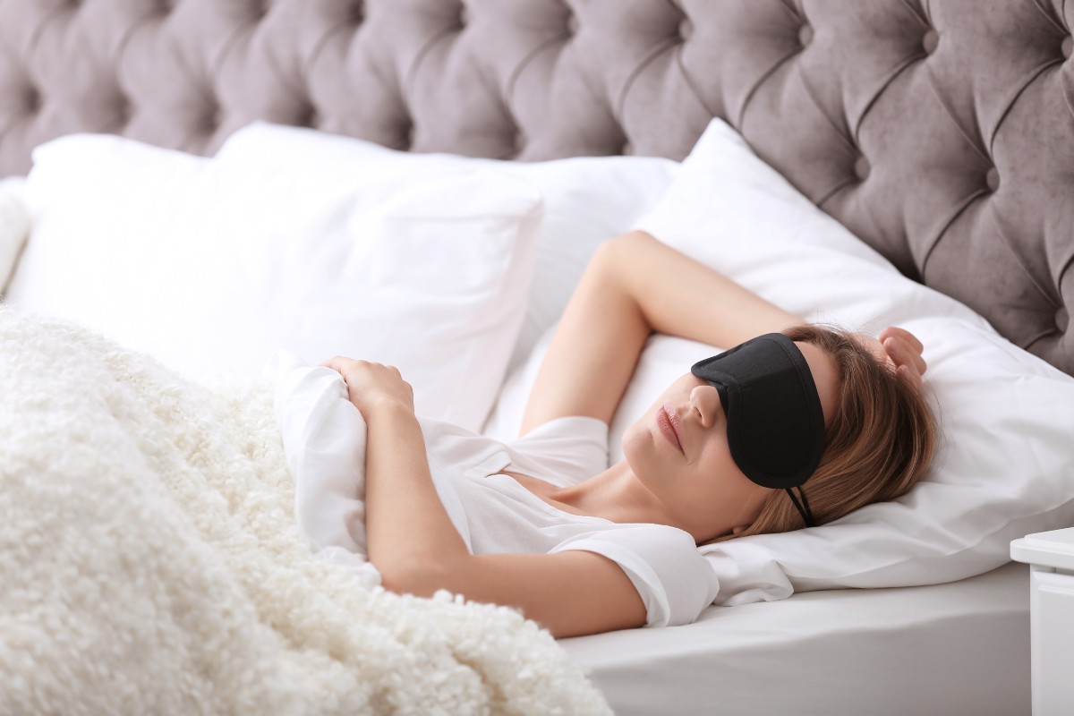 A woman enjoying a little lie in in the morning while wearing an eye mask for sleep