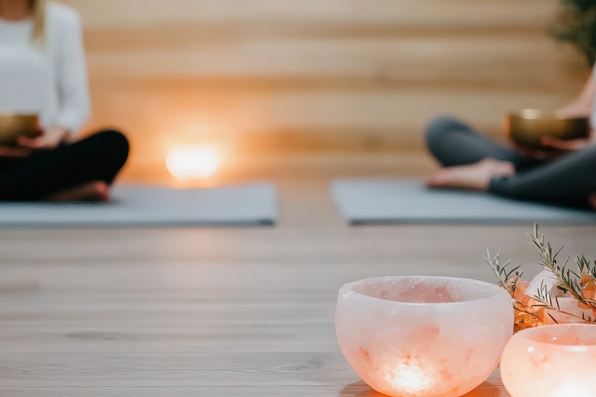 Two people sat crossed-legged on yoga mats during a meditational sound bath.