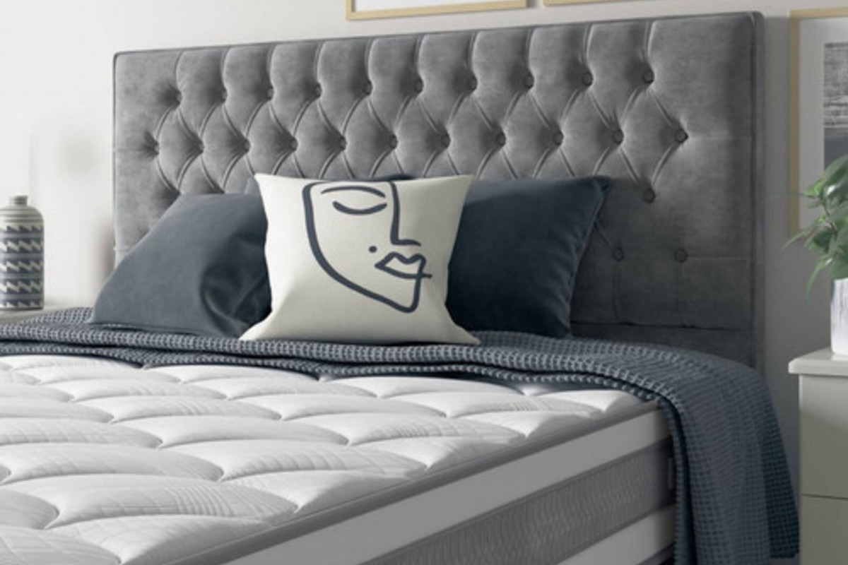 A close up of a deep buttoned, grey, floor-standing headboard