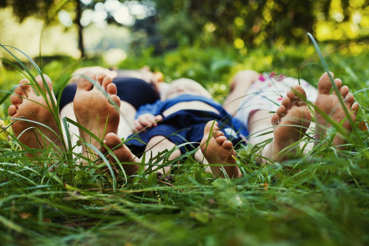 A family of 3, 2 parents and a child, lying in the grass on a summer's day