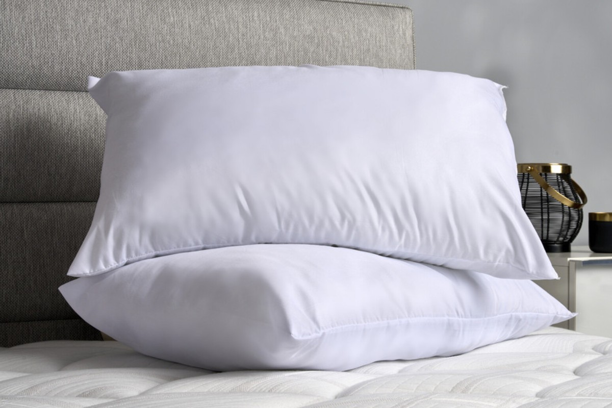 Two soft white pillows are neatly stacked on a bed in a calm, modern bedroom.