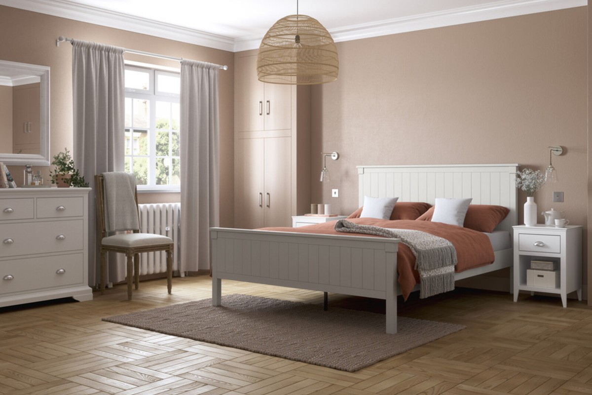 A white wooden bed frame in a calming bedroom design with wooden floors and matching white furniture